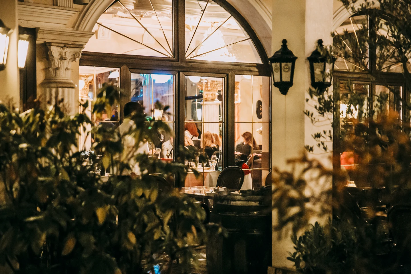 Blick durch die Rundbogenfenster in das abendlich beleuchtete Restaurant