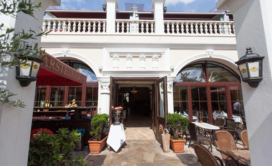 Eingang zum Restaurant zwischen weißen Rundbogenfenstern