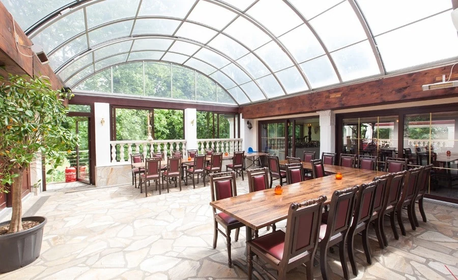 Heller Wintergarten mit langen Tafeln und Blick ins Grüne